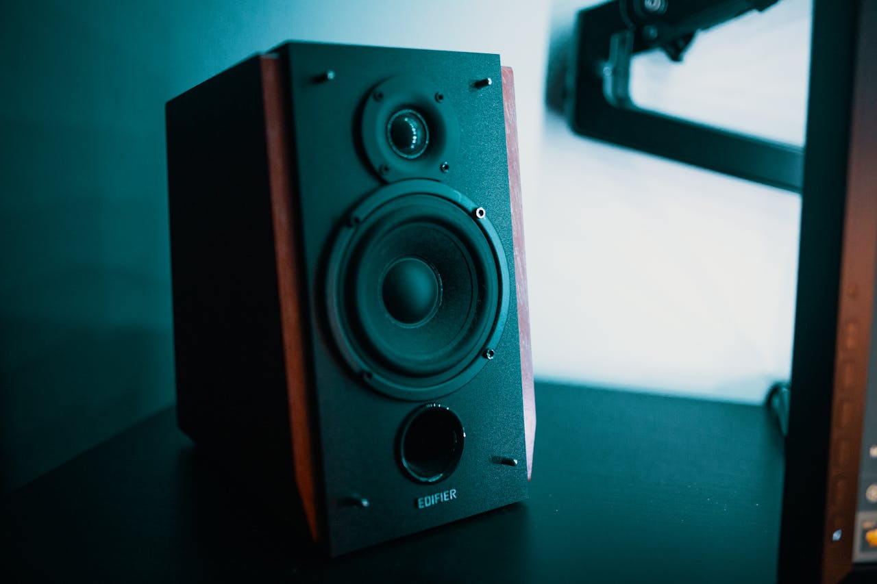 Contemporary style music speaker with round diffuser and dust cap on dark desk in flat